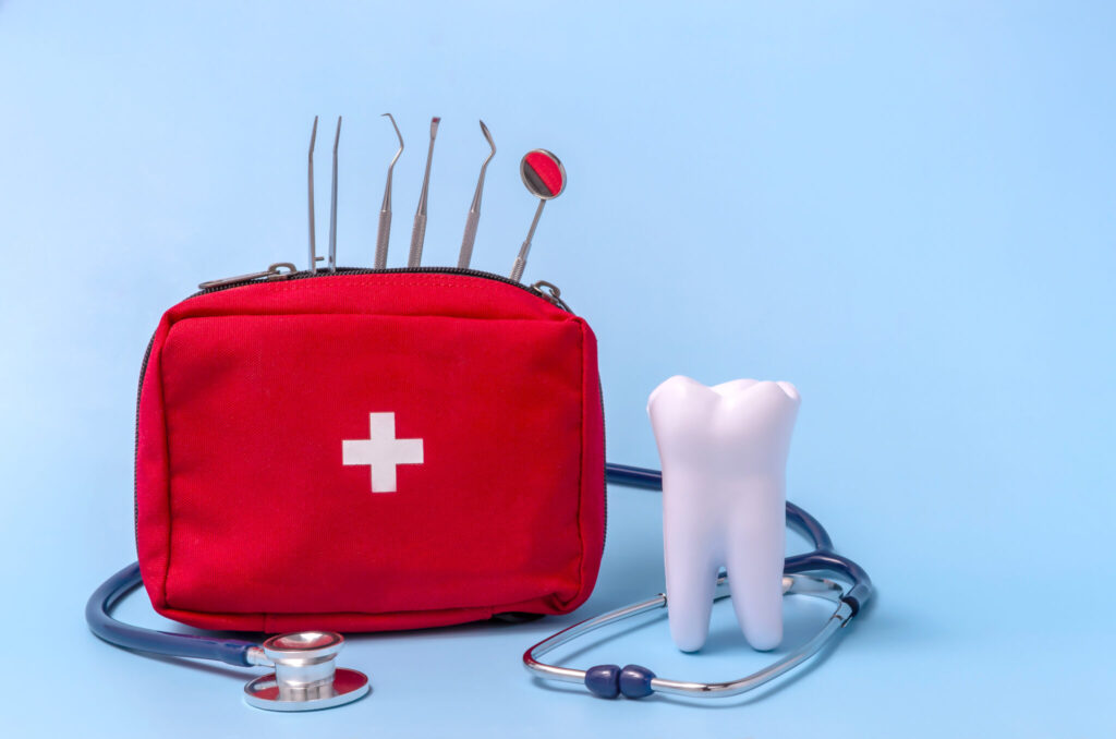 A red emergency dentistry kit with a white cross on it is sitting on a blue table.
